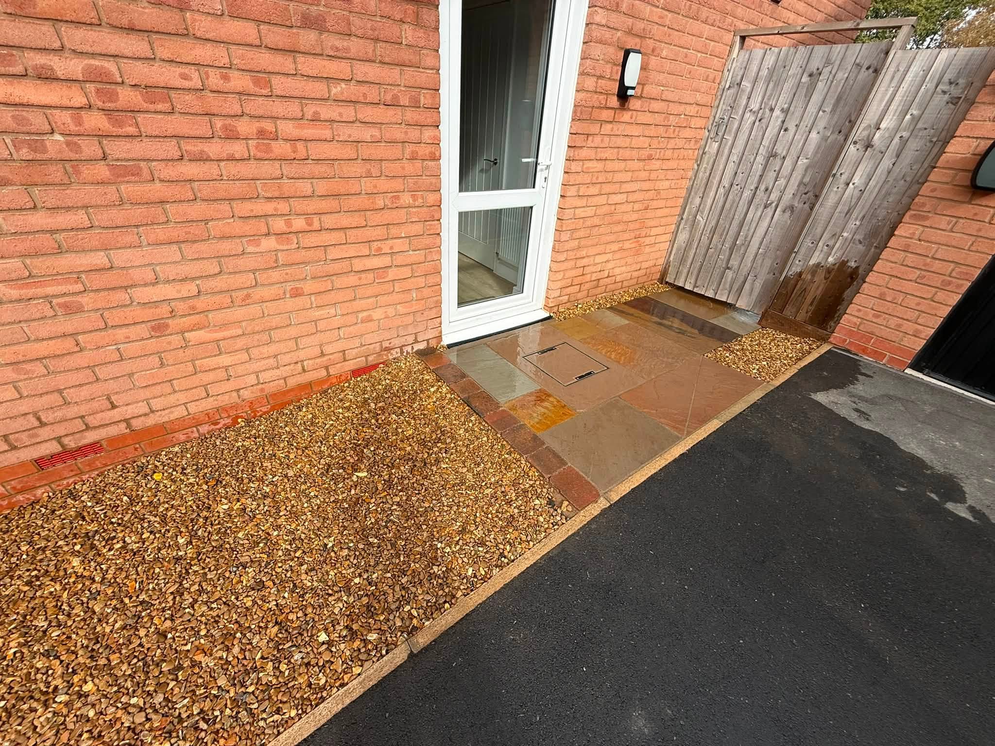 Side area finished with gravel and a paved path by the back door