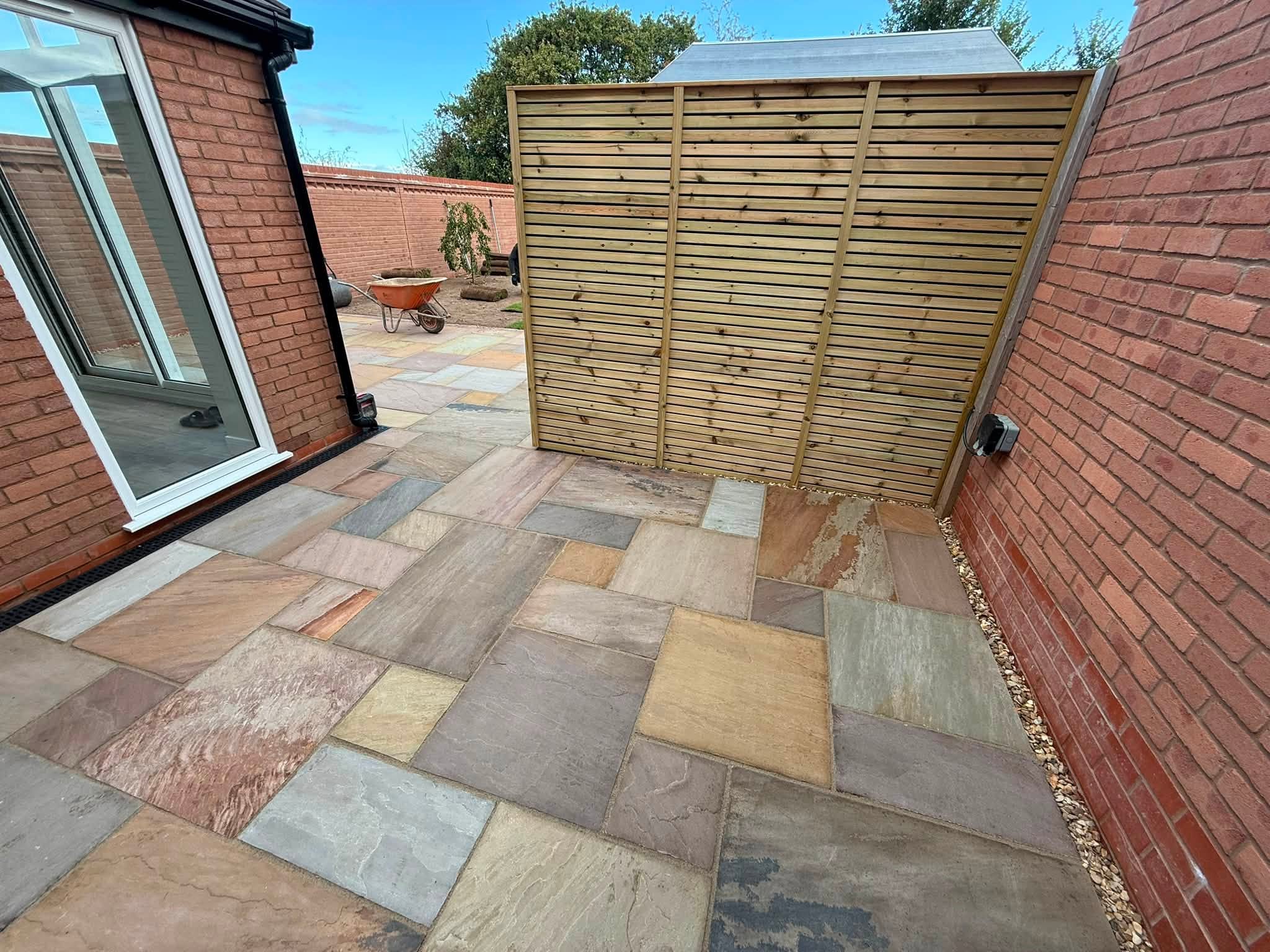 Multicolour sandstone patio beside a slatted timber screen