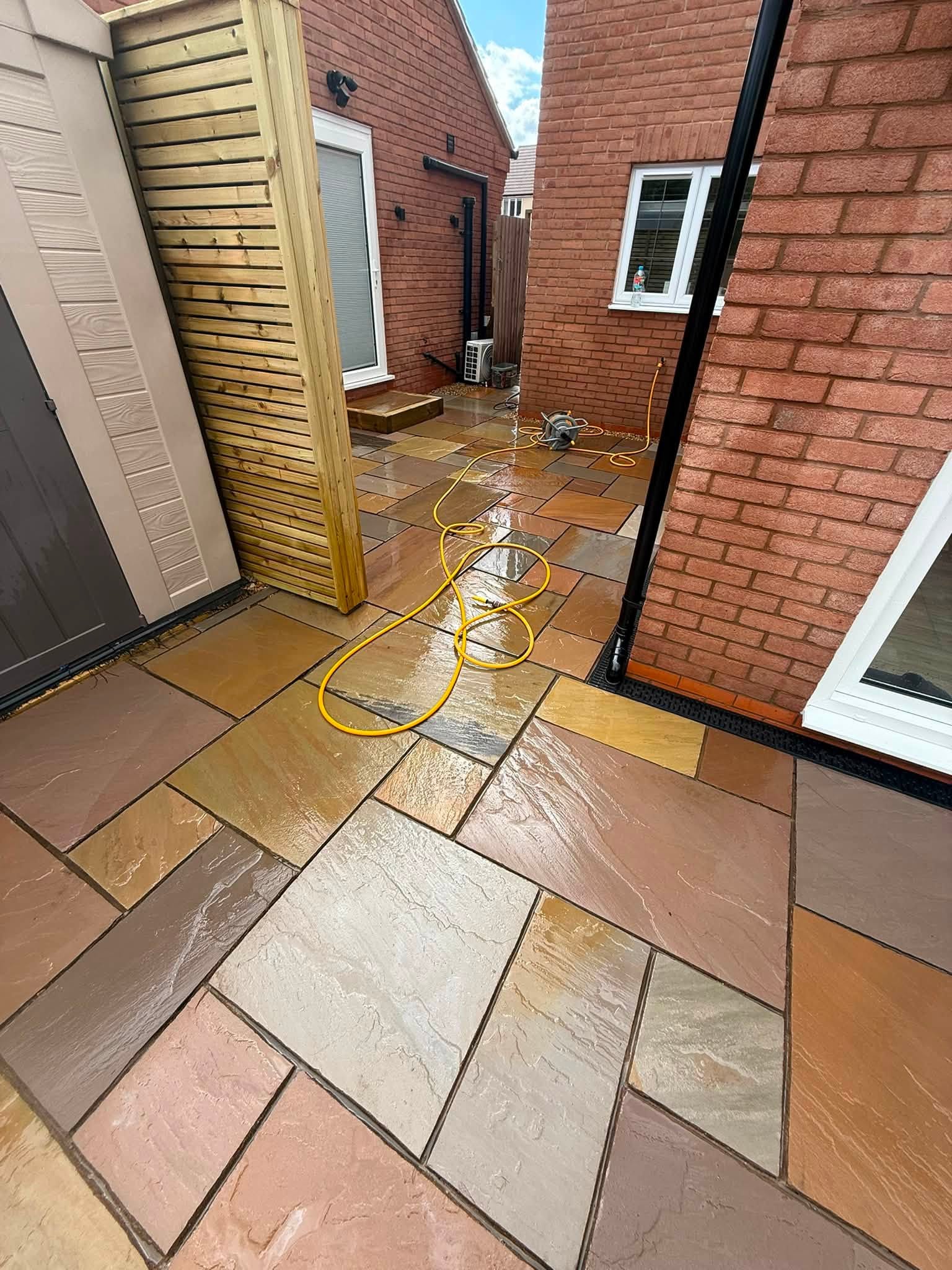 Wet multicolour sandstone path along the side of a house